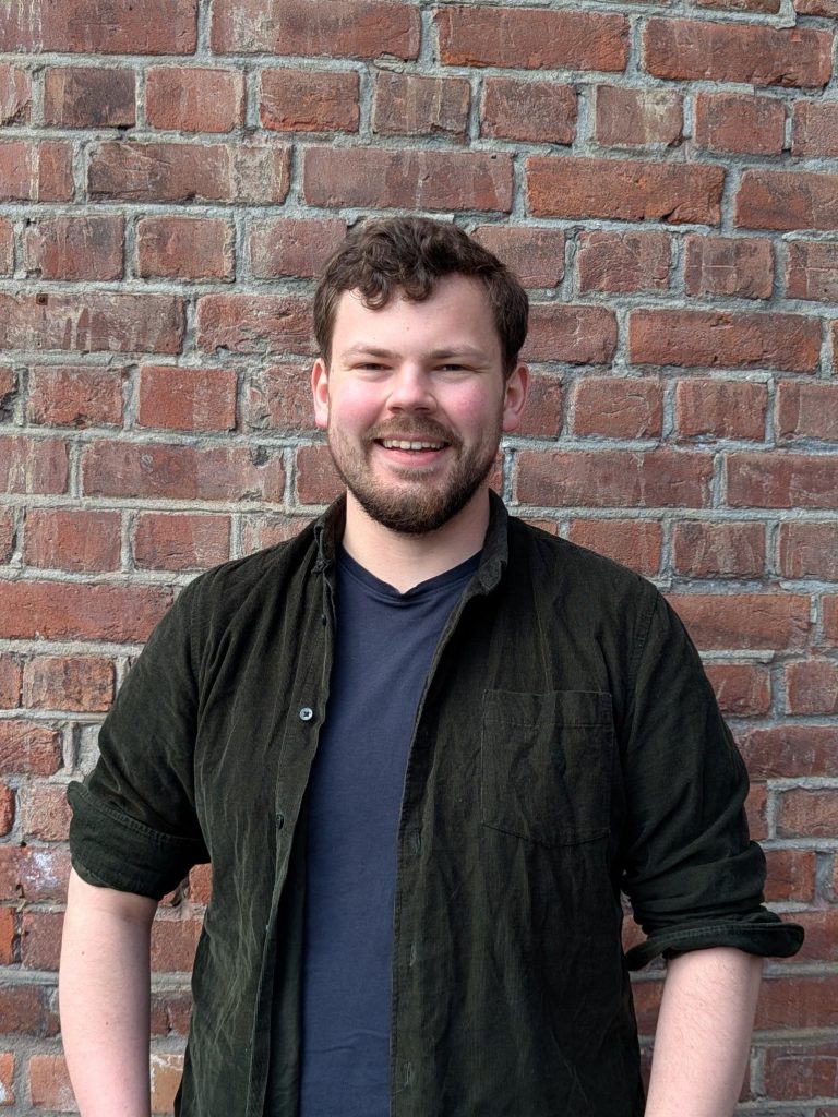 Audun Hammer Hovda smilende foran en murvegg.